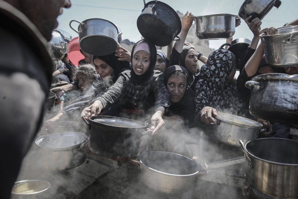 Palestinians hold out pots and pans to collect free food from a charity kitchen in Gaza, the Gaza Strip, on Monday. Palestinians hold out pots and pans to collect free food from a charity kitchen in Gaza, the Gaza Strip, on Monday.