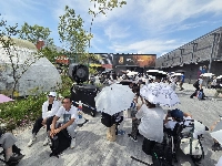 People huddle near a large fan blowing icy-cold mist at the Osaka Expo on July 12. Amid Japan's relentless summer heat, organizes have put myriad measures in place in order to keep guests safe.  | Joel Tansey