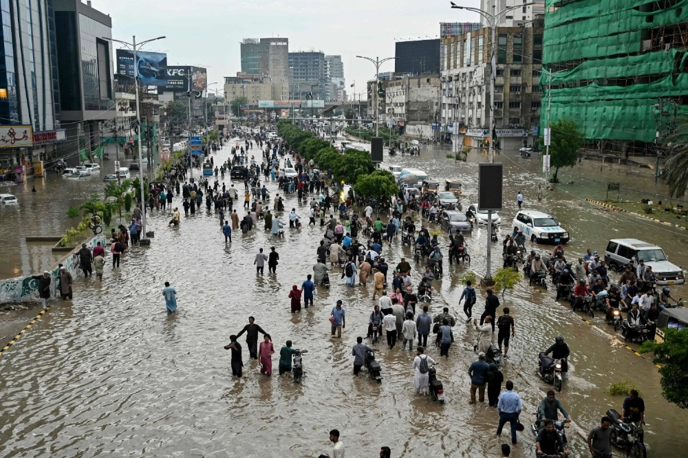 People wade through a flooded street after heavy rainfall in Karachi on Tuesday. People wade through a flooded street after heavy rainfall in Karachi on Tuesday.