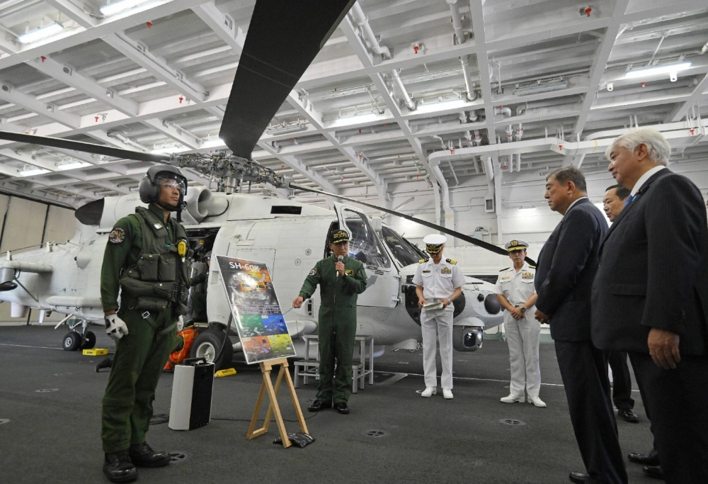 Defense Minister Gen Nakatani (right) and Prime Minister Shigeru Ishiba (second from right) inspect the Maritime Self-Defense Force helicopter carrier Kaga and receive an explanation about the SH-60K patrol helicopter in the hangar at the MSDF's Yokosuka base in Kanagawa Prefecture on Saturday. Defense Minister Gen Nakatani (right) and Prime Minister Shigeru Ishiba (second from right) inspect the Maritime Self-Defense Force helicopter carrier Kaga and receive an explanation about the SH-60K patrol helicopter in the hangar at the MSDF's Yokosuka base in Kanagawa Prefecture on Saturday.