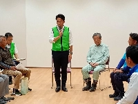 Shinjiro Koizumi, flanked by Liberal Democratic Party Secretary-General Hiroshi Moriyama, greets rice farmers during a discussion in the city of Kirishima, Kagoshima Prefecture, on Monday. | JIJI