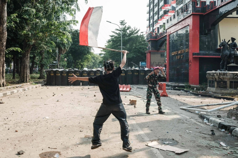 A man waves Indonesia's national flag during clashes with riot police on Friday in Jakarta following the death of a motorcycle taxi driver. A man waves Indonesia's national flag during clashes with riot police on Friday in Jakarta following the death of a motorcycle taxi driver.