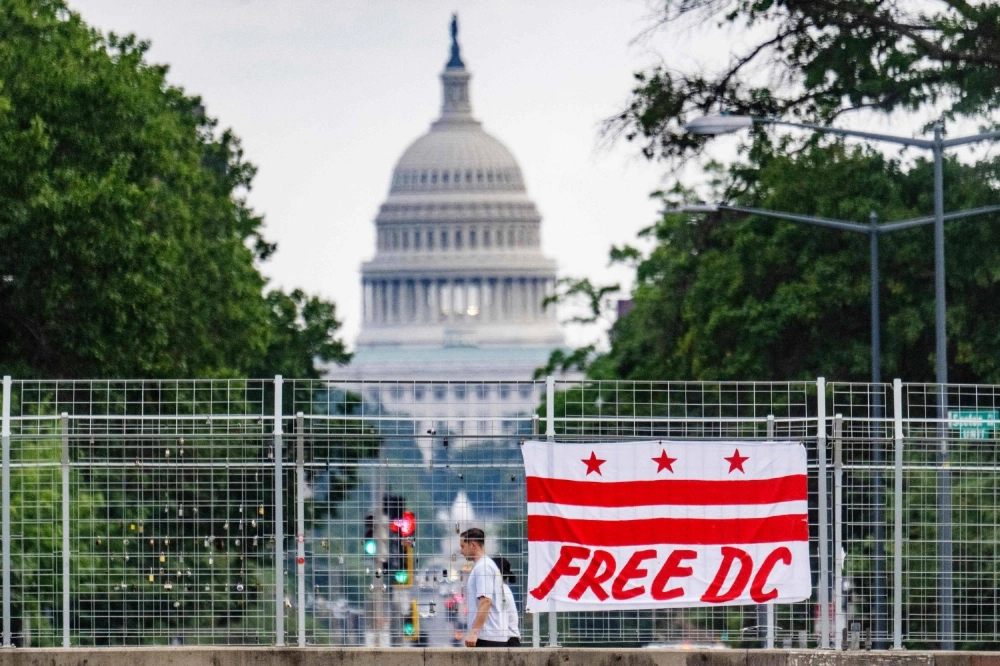 Pedestrians walk past a flag that reads “Free DC” hanging on an overpass near the U.S. Capitol building in Washington on Aug. 15 Pedestrians walk past a flag that reads “Free DC” hanging on an overpass near the U.S. Capitol building in Washington on Aug. 15