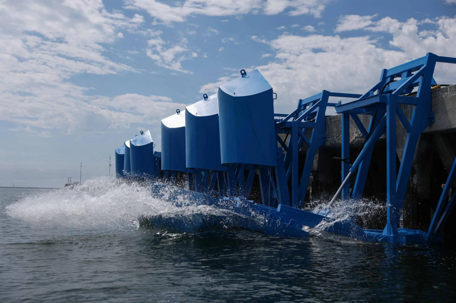 Floating blue paddles dance on the waves that lap a dock in the Port of Los Angeles, silently converting the power of the sea into useable electricity. Floating blue paddles dance on the waves that lap a dock in the Port of Los Angeles, silently converting the power of the sea into useable electricity.