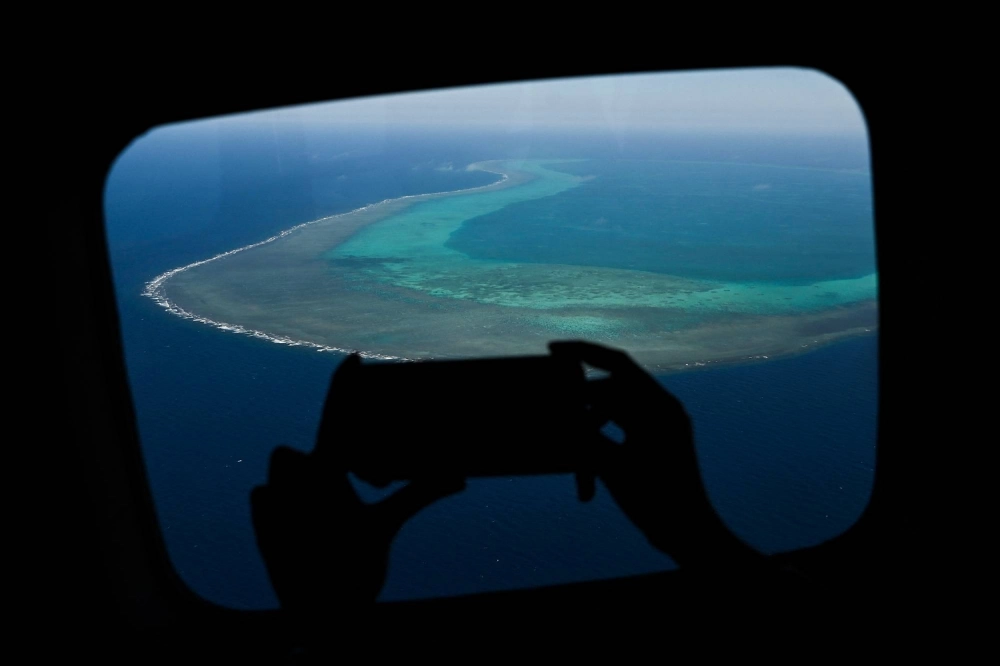 A reporter records video over Scarborough Shoal in the disputed South China Sea in February 2024.  A reporter records video over Scarborough Shoal in the disputed South China Sea in February 2024.