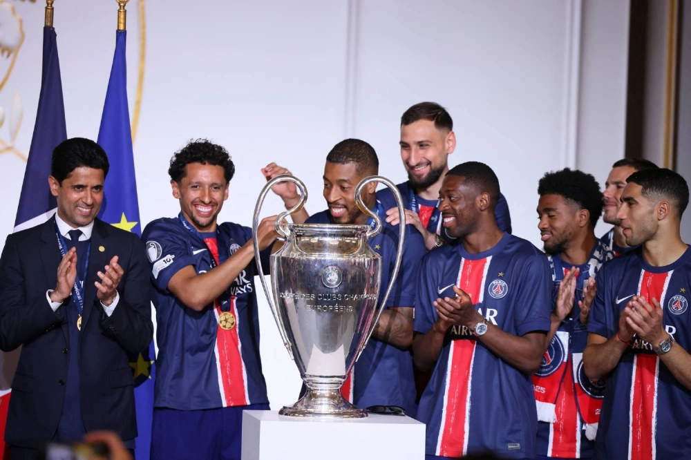 Paris Saint-Germain players and officials celebrate with the Champions League trophy at the Elysee Palace in Paris in June.  Paris Saint-Germain players and officials celebrate with the Champions League trophy at the Elysee Palace in Paris in June.