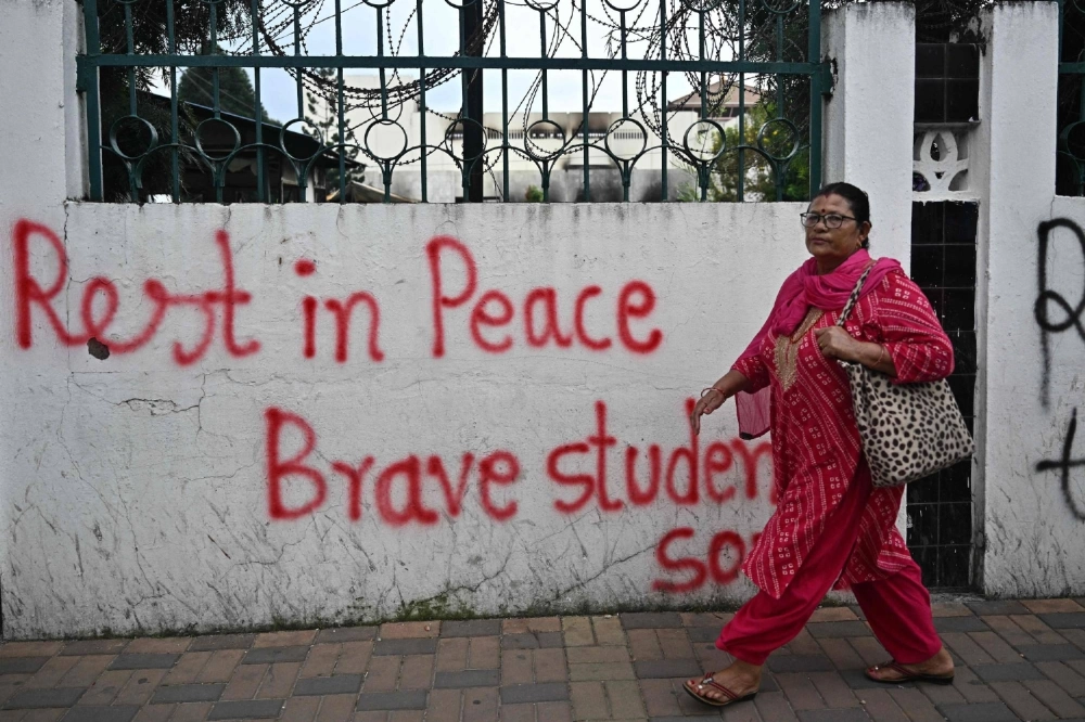 A woman passes a graffitied wall outside Nepal's torched Parliament in Kathmandu on Sunday. The country's new leader, Sushila Karki, vowed the same day to follow protesters' demands to "end corruption" as she began work as interim prime minister. A woman passes a graffitied wall outside Nepal's torched Parliament in Kathmandu on Sunday. The country's new leader, Sushila Karki, vowed the same day to follow protesters' demands to "end corruption" as she began work as interim prime minister.
