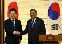 South Korean President Lee Jae Myung (left) and Prime Minister Shigeru Ishiba shake hands during a joint news conference in Tokyo in August. | BLOOMBERG