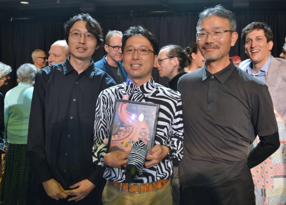 (From left) Kazato Oishi, associate professor at Kyoto University's Graduate School of Agriculture; Tomoki Kojima of the National Agriculture and Food Research Organization; and Sei Sato of the Aichi prefectural livestock research center at the award ceremony for the Ig Nobel Prize in Boston, Massachusetts, on Thursday (From left) Kazato Oishi, associate professor at Kyoto University's Graduate School of Agriculture; Tomoki Kojima of the National Agriculture and Food Research Organization; and Sei Sato of the Aichi prefectural livestock research center at the award ceremony for the Ig Nobel Prize in Boston, Massachusetts, on Thursday