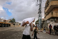 A Palestinian boy carries a sack of wheat flour in Gaza | BLOOMBERG