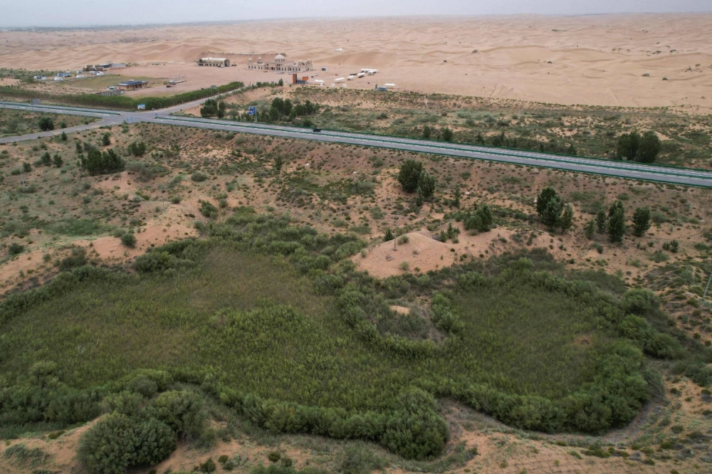 An aerial view shows the contrast between the green zone and the desert landscape of the Kubuqi Desert, in Ordos, in China's northern Inner Mongolia region. An aerial view shows the contrast between the green zone and the desert landscape of the Kubuqi Desert, in Ordos, in China's northern Inner Mongolia region.
