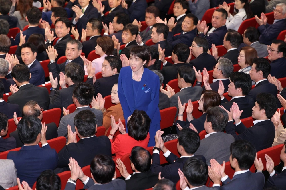 Newly-elected Liberal Democratic Party chief Sanae Takaichi greets her fellow LDP members on Saturday at party headquarters.  Newly-elected Liberal Democratic Party chief Sanae Takaichi greets her fellow LDP members on Saturday at party headquarters.