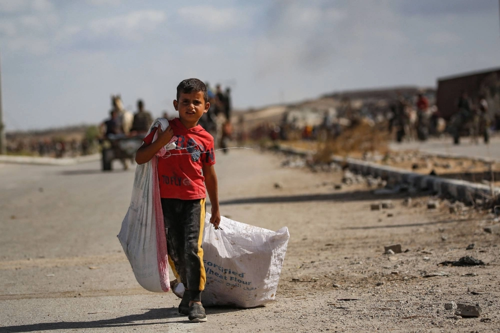 A Palestinian boy  returns from a food distribution point run by the U.S. and Israeli-backed Gaza Humanitarian Foundation group in the central Gaza Strip on Sunday. 
 A Palestinian boy  returns from a food distribution point run by the U.S. and Israeli-backed Gaza Humanitarian Foundation group in the central Gaza Strip on Sunday.
