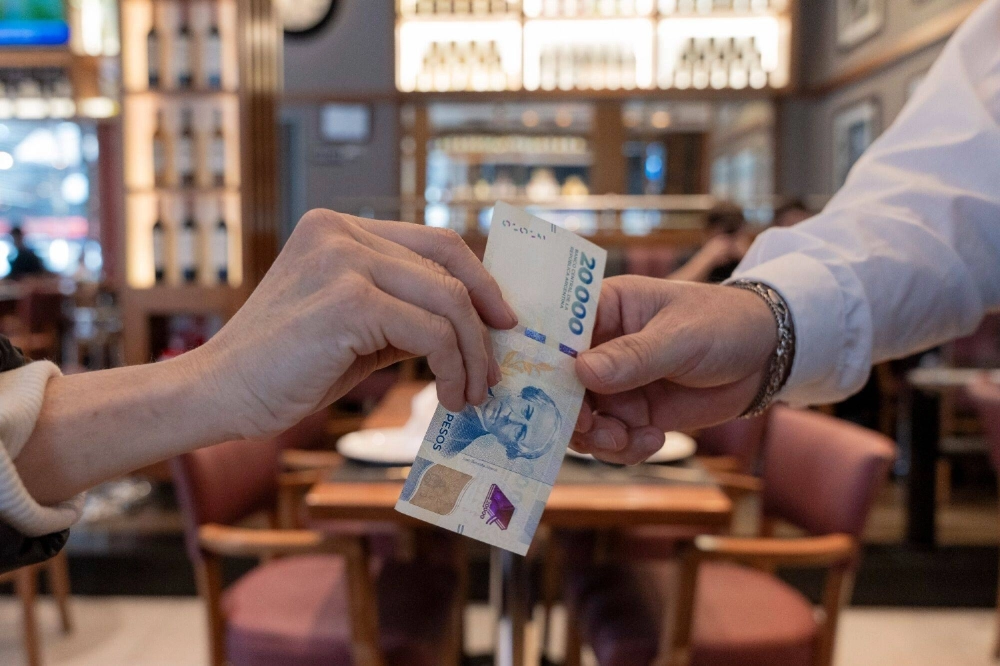 A customer pays for a coffee at a bar in Buenos Aires on Sept. 23. Many Argentines are traveling to Rio de Janeiro, Miami and the Uruguayan beach town of Punta del Este but, when it comes to shopping trips, most go to the Chilean capital of Santiago. A customer pays for a coffee at a bar in Buenos Aires on Sept. 23. Many Argentines are traveling to Rio de Janeiro, Miami and the Uruguayan beach town of Punta del Este but, when it comes to shopping trips, most go to the Chilean capital of Santiago.