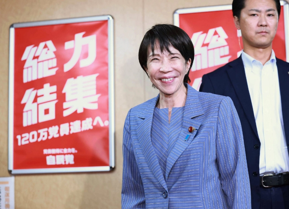Liberal Democratic Party President Sanae Takaichi (center) speaks to reporters on Sunday after meeting Taro Aso, the party's supreme advisor, at the party's headquarters. Liberal Democratic Party President Sanae Takaichi (center) speaks to reporters on Sunday after meeting Taro Aso, the party's supreme advisor, at the party's headquarters.