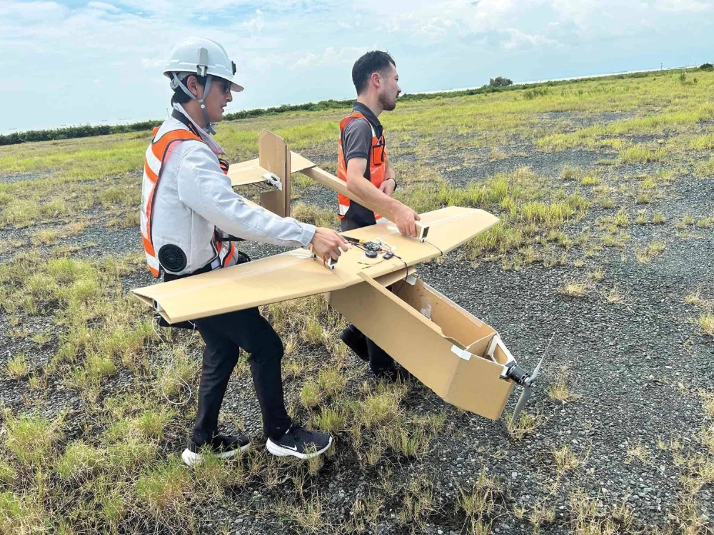 Takumi Yamaguchi (right), head of startup AirKamuy, and a colleague retrieve a drone made of cardboard after a test flight in a field near Nagoya. Takumi Yamaguchi (right), head of startup AirKamuy, and a colleague retrieve a drone made of cardboard after a test flight in a field near Nagoya.