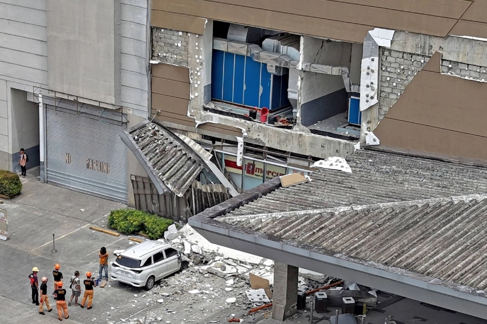 Authorities inspect a damaged wall and a car outside a mall in Butuan, Philippines, on Friday, after a major earthquake struck the area.  Authorities inspect a damaged wall and a car outside a mall in Butuan, Philippines, on Friday, after a major earthquake struck the area.
