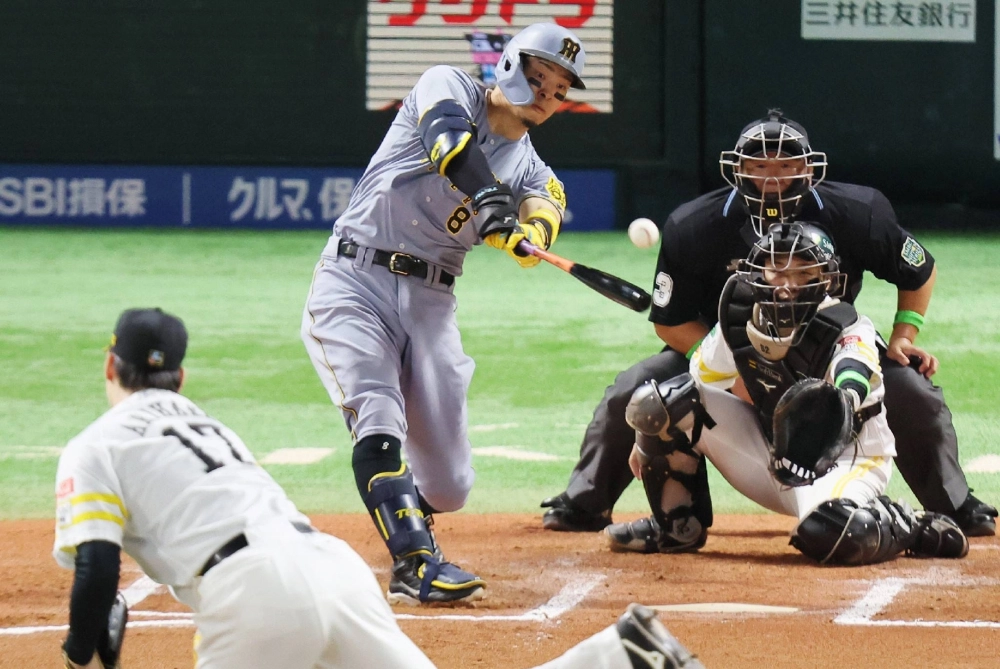 The Tigers' Teruaki Sato hits an RBI double against the Hawks during the sixth inning in Game 1 of the Japan Series in Fukuoka on Saturday. The Tigers' Teruaki Sato hits an RBI double against the Hawks during the sixth inning in Game 1 of the Japan Series in Fukuoka on Saturday.