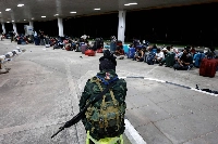 A Thai soldier keeps watch over people who crossed over from Myanmar, as they wait to be screened and interrogated by officials on Oct. 23. | AFP-JIJI