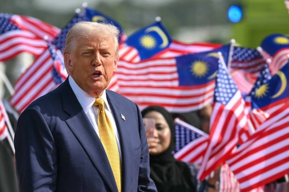 U.S. President Donald Trump looks on next to people waving Malaysian national flags before he departs from Kuala Lumpur International Airport on Monday. U.S. President Donald Trump looks on next to people waving Malaysian national flags before he departs from Kuala Lumpur International Airport on Monday.