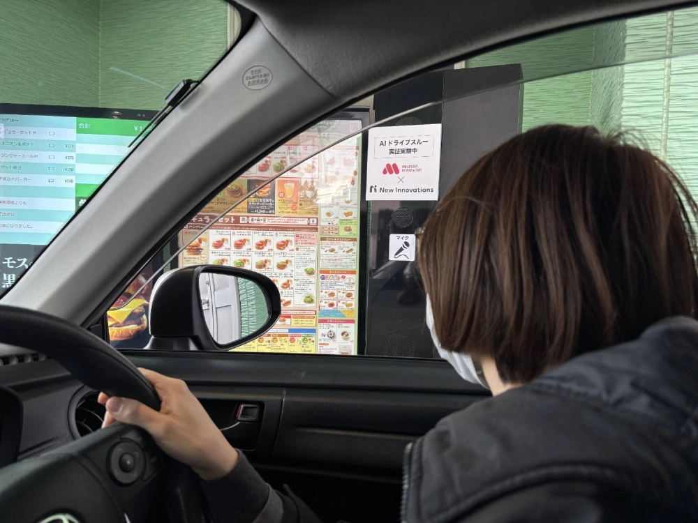 A Mos Food Services employee places an order via a microphone at an artificial intelligence drive-thru facility, which was unveiled to members of the media in Yoshikawa City, Saitama Prefecture, on Wednesday.