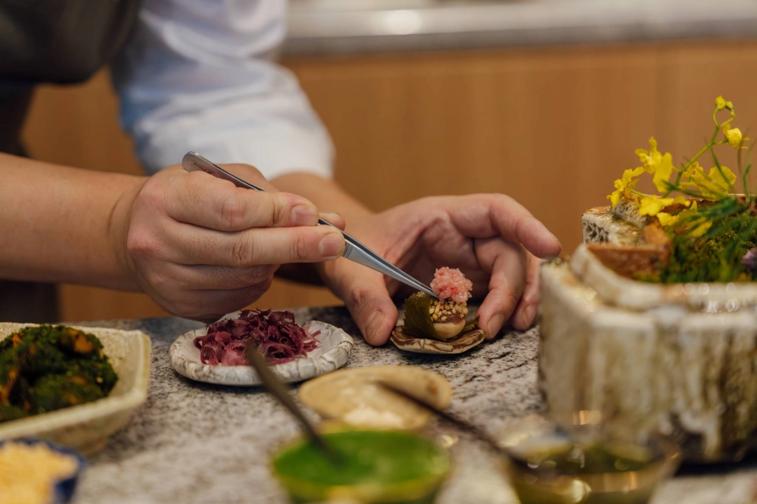 Keita Tominaga assembles a morsel of lily bulb paste, duck liver parfait and fried cherry blossom. Keita Tominaga assembles a morsel of lily bulb paste, duck liver parfait and fried cherry blossom.