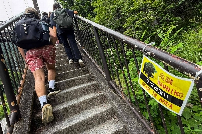 Hikers walk past a bear warning sign in the Okutama area in western Tokyo on Sunday as local authorities urge visitors to take precautions following increased reports of bear sightings in the region.