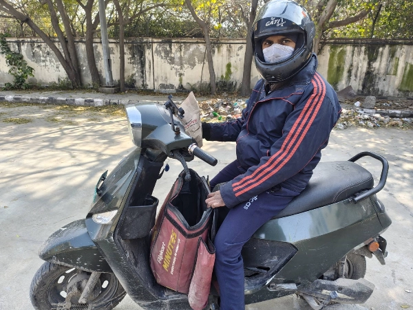 Image 16: Rohit Kushwaha waits for a customer as he delivers his last parcel of the day, in New Delhi in January. His work as a delivery driver has helped pay the family’s bills, but has had a significant impact on his health.