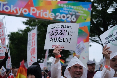 Image 25: A Tokyo Pride parade participant holds a sign that says "we want to be a married couple, not a couple."
