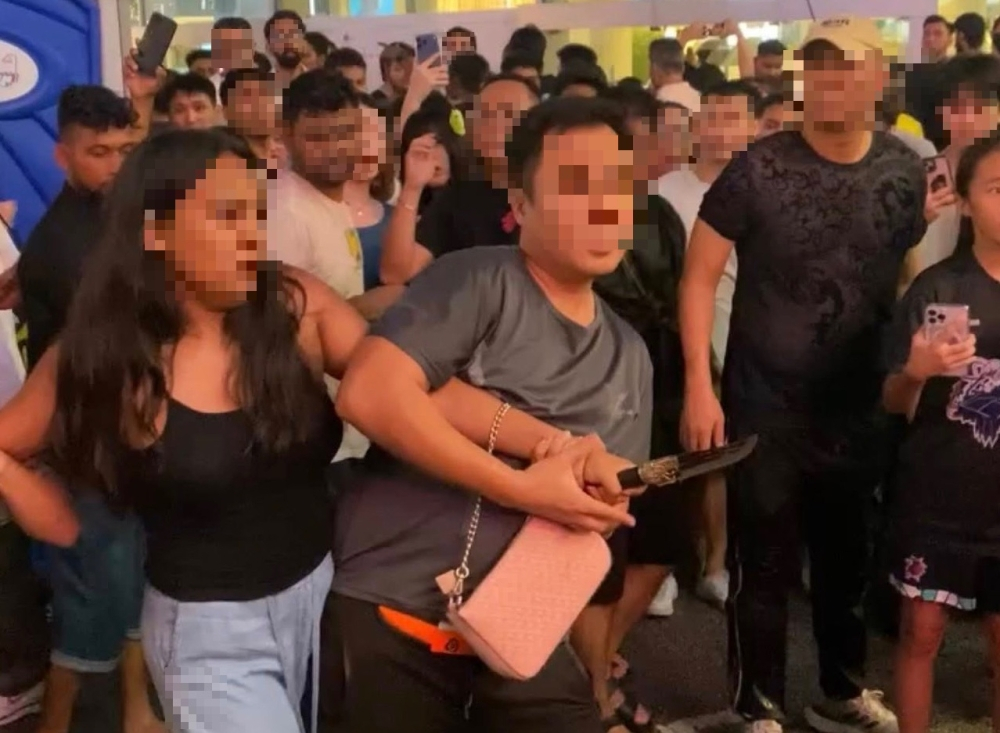 Knife-wielding woman at Rain Rave charged, ordered to undergo psychiatric assessment A bystander restrains a woman allegedly carrying a knife during the Rain Rave Water Music Festival in Bukit Bintang before police officers arrived at the scene. — Viral video screen grab