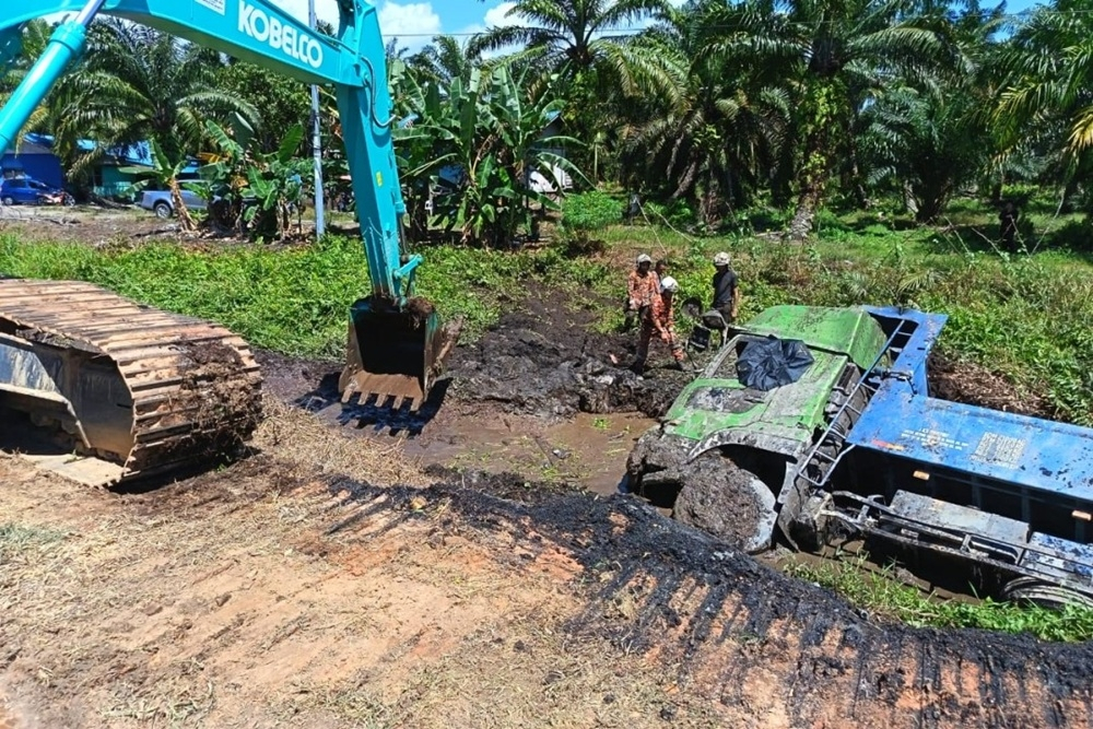 Trapped lorry driver found dead after premix‑laden truck overturns into muddy ditch in Sebuyau Rescuers use an excavator to extricate the lorry driver. — Picture courtesy of Fire and Rescue Department