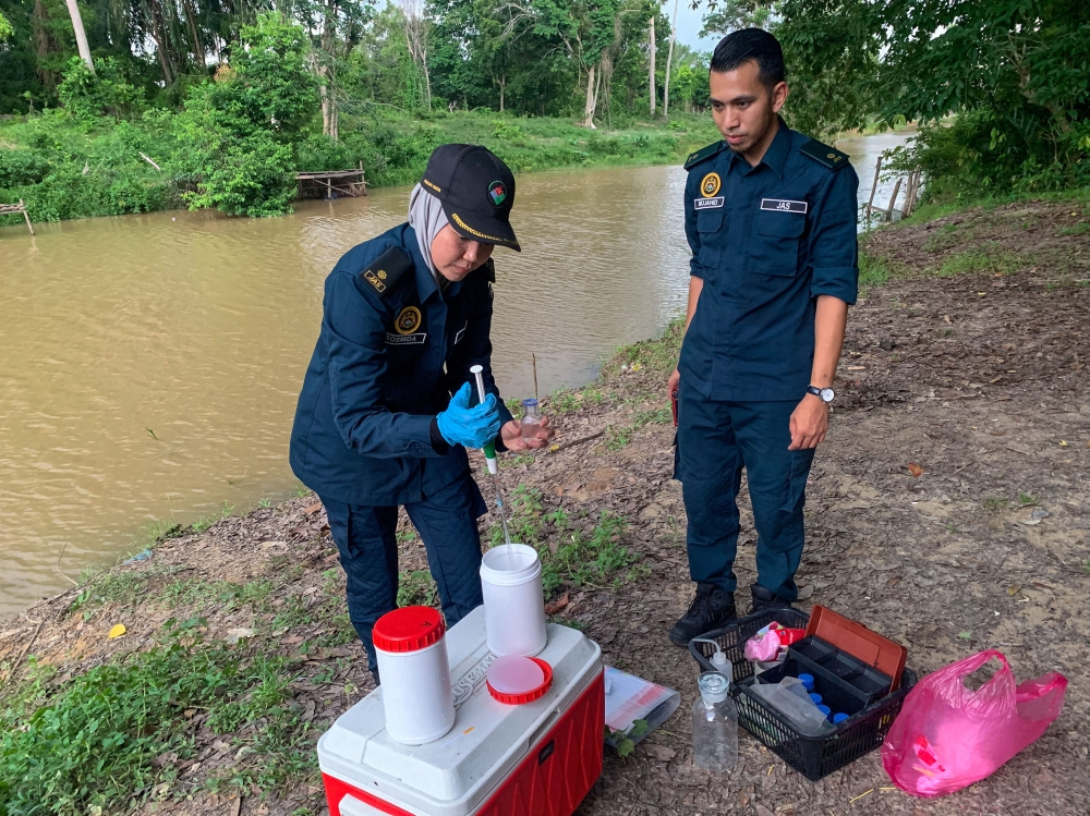 Mass fish deaths in Sungai Padang Kijang trigger DOE probe Department of Environment Operations Division 2 Complaints Unit officer Rosmida Ab Razak (left) and Mohd Mujahid Mohamed Aziz (right) collecting river water samples from Sungai Padang Kijang near Kampung Alor Pasir, where alleged pollution is believed to have caused the deaths of hundreds of fish. — Bernama pic