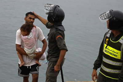 Hundreds of unaccompanied minors endure harsh conditions in Ceuta migrant influx A member of Moroccan security forces gestures to a man carrying a child close to the site of clashes near Fnideq, on the Morocco-Spain border July 31, 2026. Hundreds of unaccompanied minors slept outdoors in a disused industrial park in Ceuta after swimming to the Spanish territory from Morocco. — AFP pic