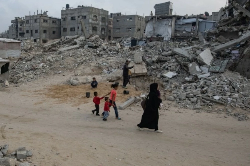 فلسطينيون يسيرون بين أنقاض منازلهم المدمرة في خان يونس.(إ ب أ)