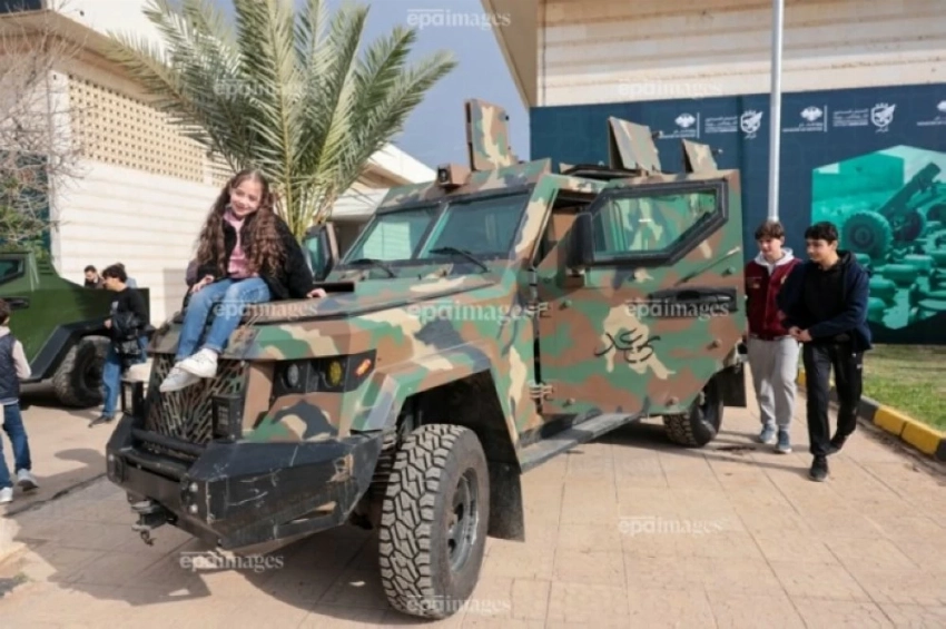 فتاة سورية تجلس على عربة عسكرية مدرعة خلال معرض عسكري في دمشق احتفالا بإسقاط بشار .(إ ب أ)