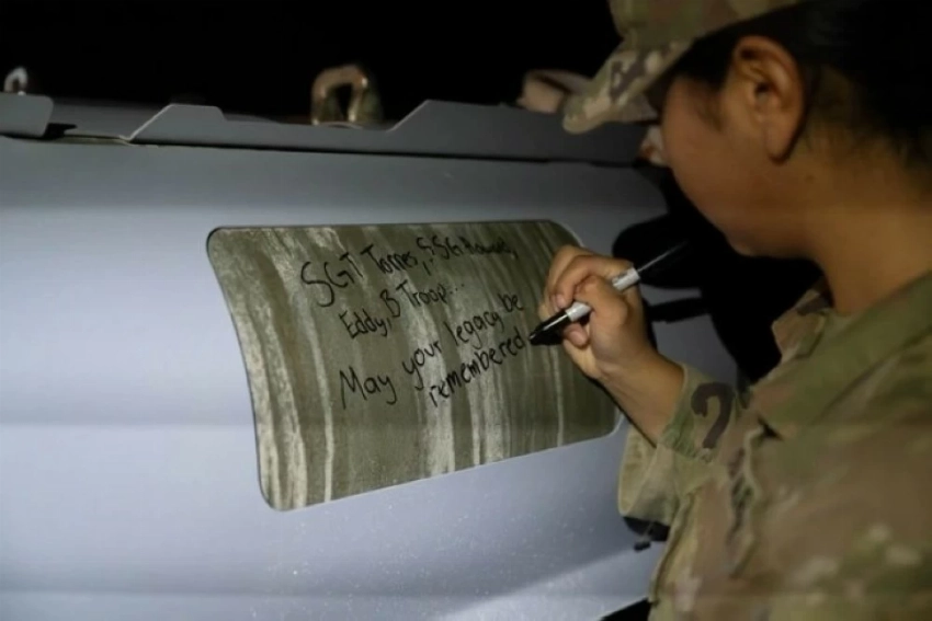 جندي أمريكي يكتب أسماء الجنديين والمدني الذين قتلوا في تدمر، على قنبلة قبيل إطلاقها نحو مواقع داعش.