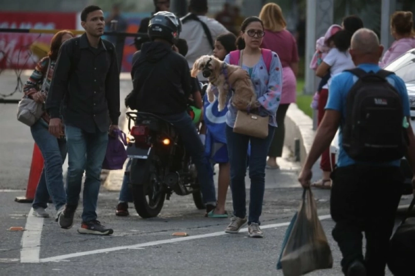 فنزويليون يسيرون عند نقطة تفتيش بالقرب من حصن تيونا الذي يضم مقر وزارة الدفاع في كاراكاس. (إ ب أ)